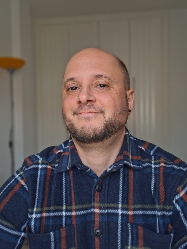 Psicólogo hombre con camisa a cuadros sentado.